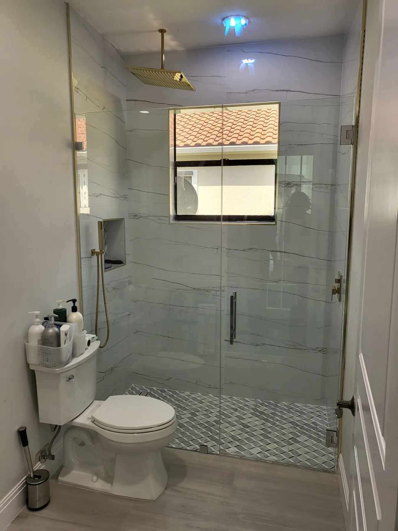 after frameless swing shower glass with brushed gold hardware in Southwest Florida