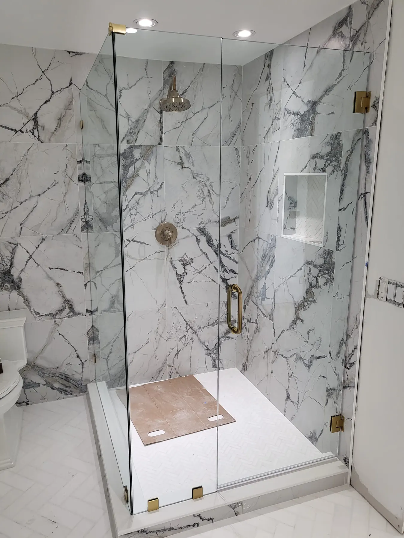after frameless swing shower glass with brushed gold hardware in Southwest Florida