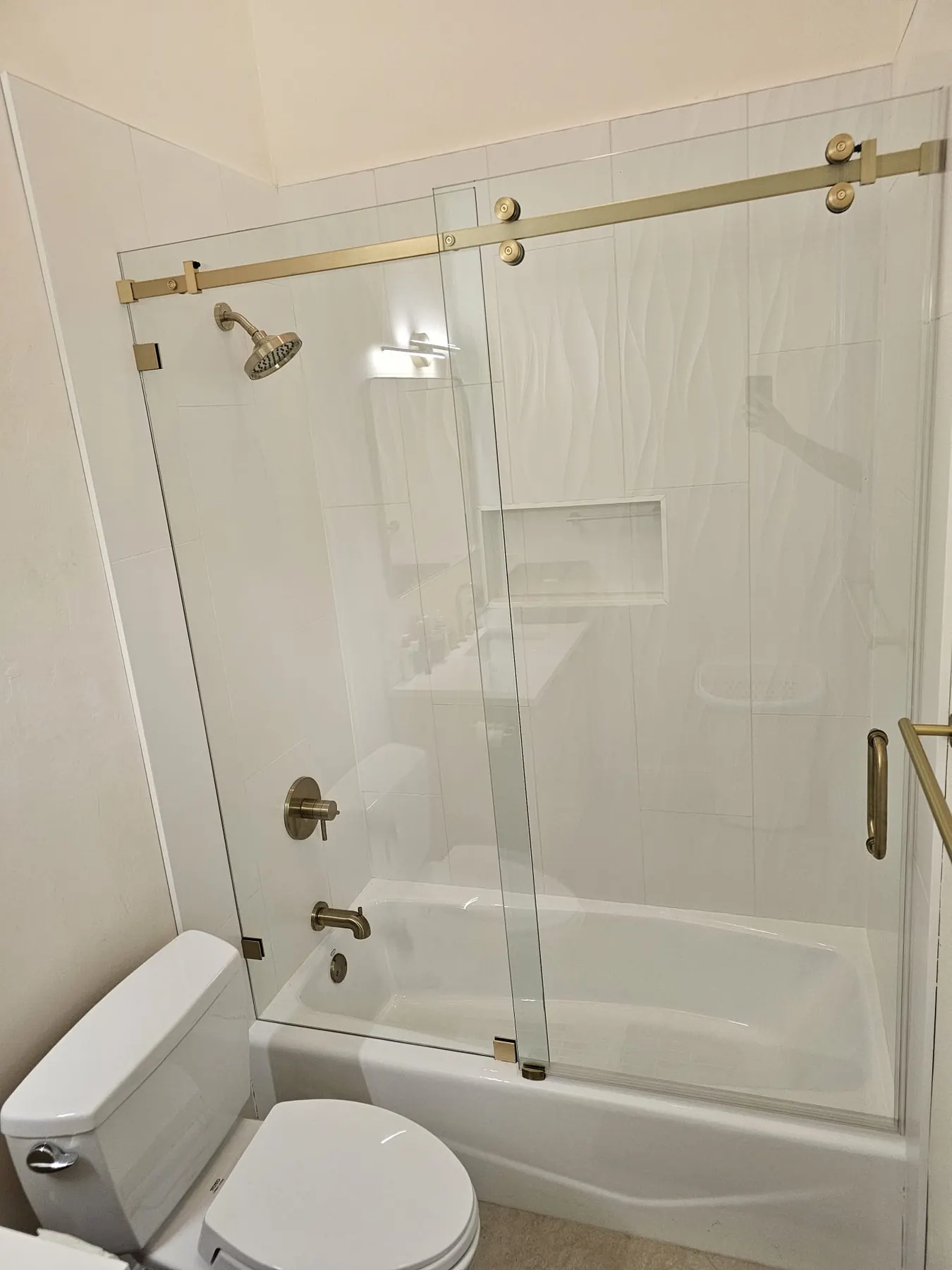 after frameless sliding shower glass with brushed gold hardware in Southwest Florida