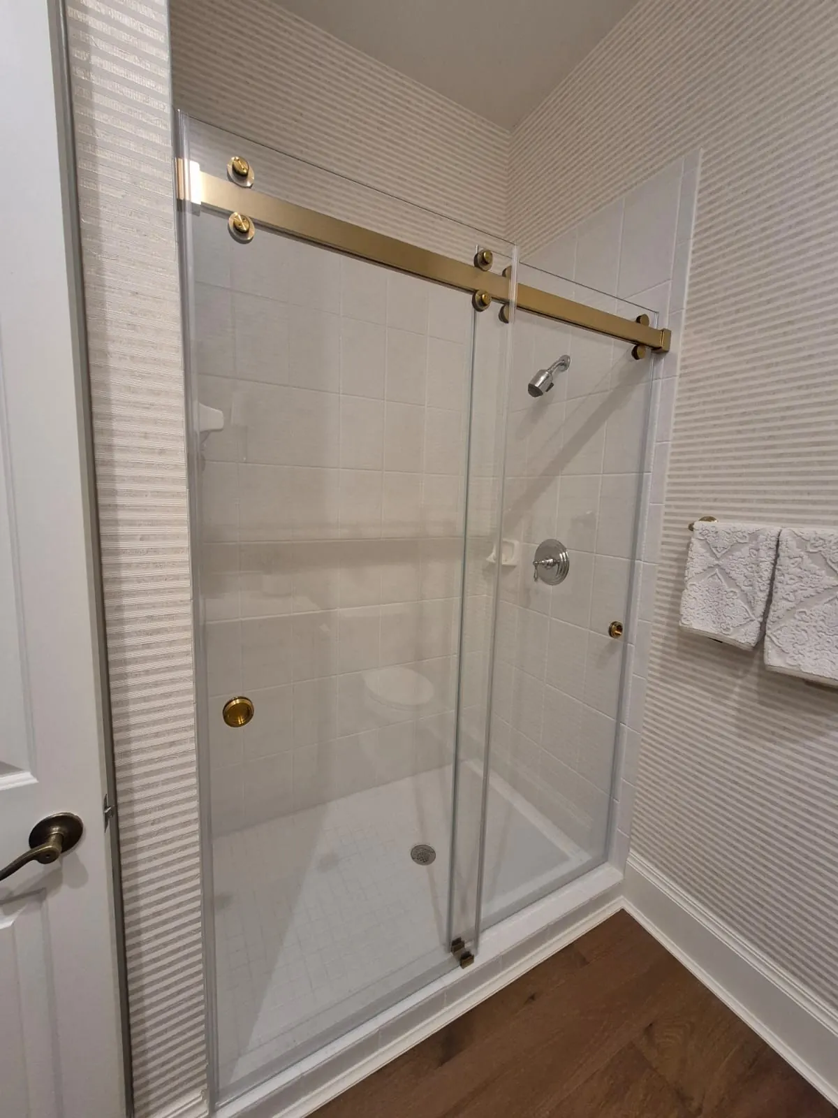 after frameless sliding shower glass with brushed gold hardware in Southwest Florida