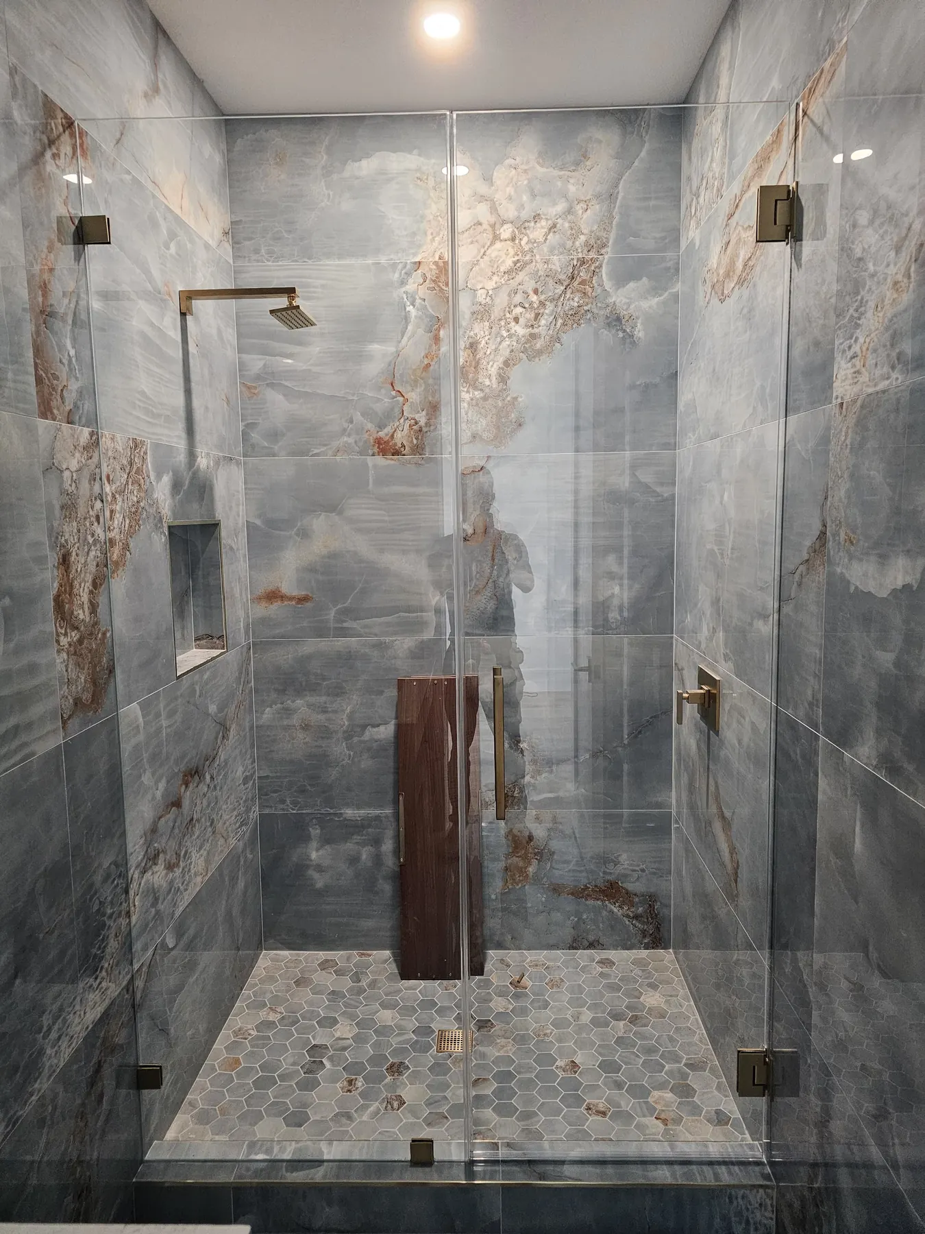 after frameless swing shower glass with brushed gold hardware in Southwest Florida