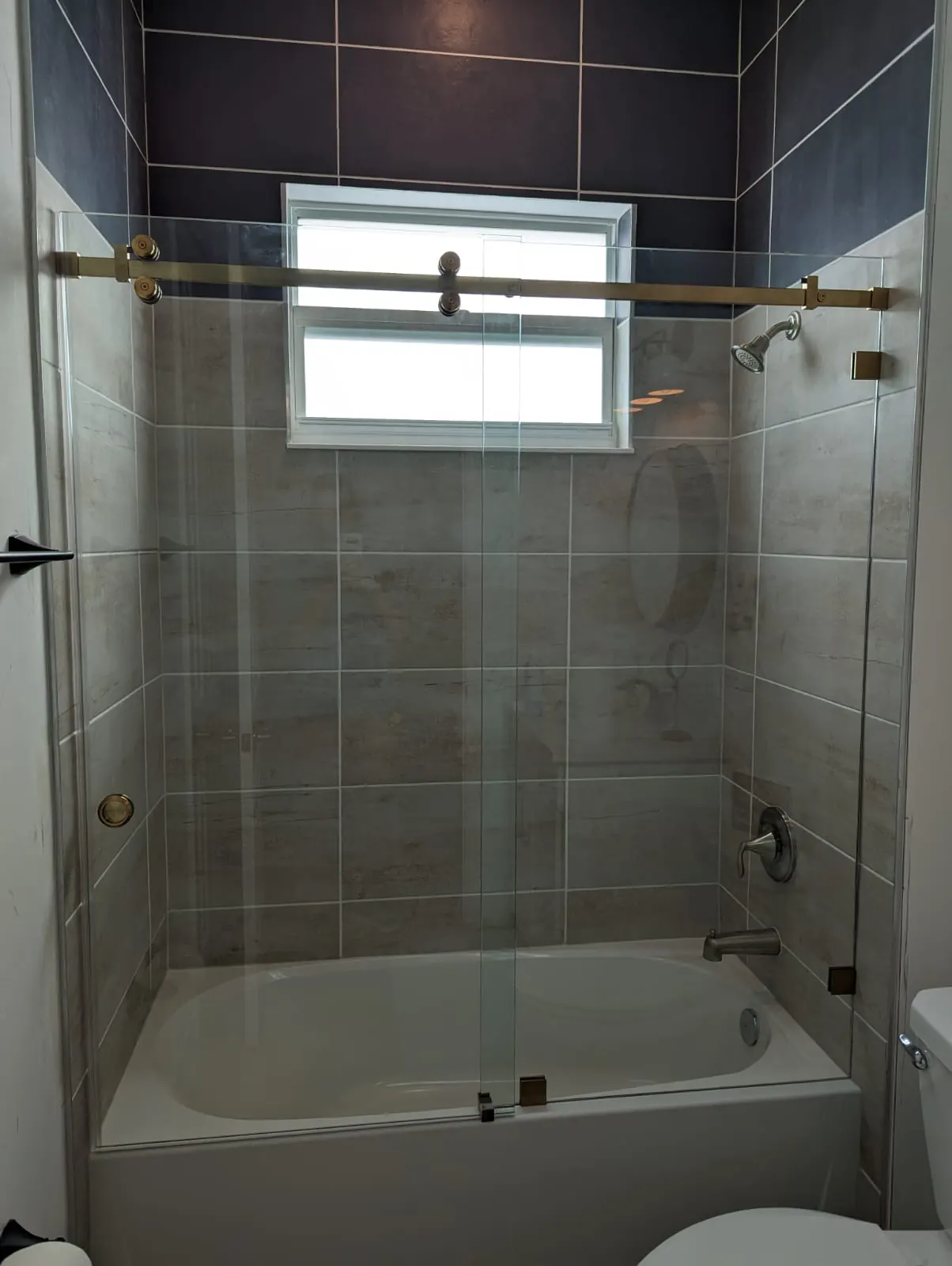 after frameless sliding shower glass with brushed gold hardware in Southwest Florida