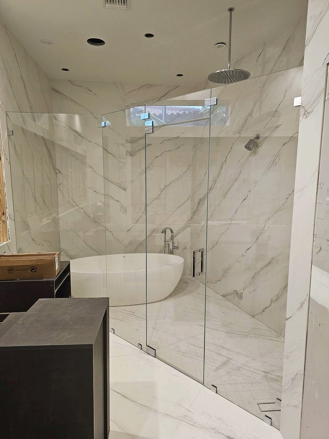 frameless glass wet room enclosure beside a freestanding tub in a Naples bathroom remodel